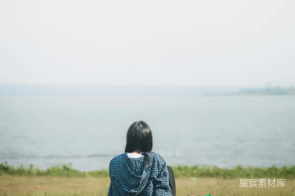 高清摄影 一个女人在阳光明媚的日子坐在水边。