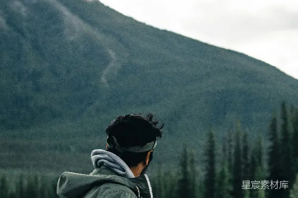 高清摄影 一个男人站在河边，背景中有一座山。