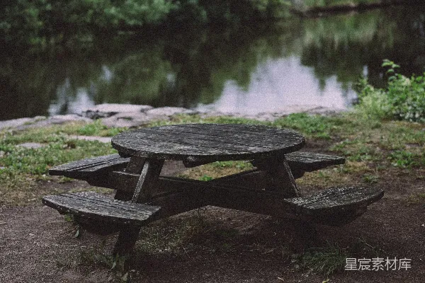 高清摄影 一张圆形木制野餐桌静静地坐落在宁静的湖边。