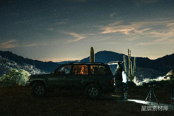 高清摄影 男人在夜晚用望远镜对着星空，旁边停着一辆SUV。