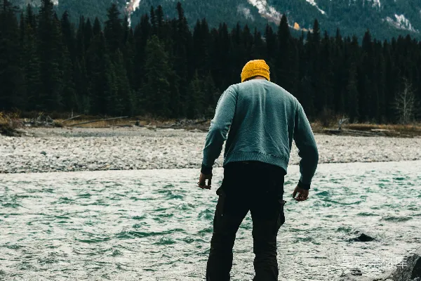 高清摄影 一个男人正在一条岩石河床上行走，背景中有一座山。