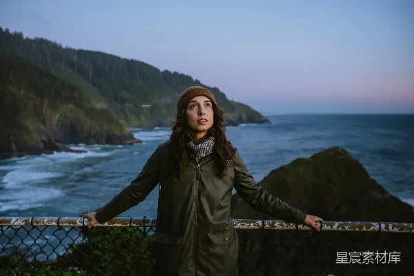 高清摄影 一个女人站在靠近海洋的栅栏上。