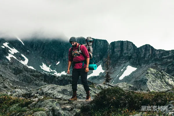 高清摄影 穿着红色夹克和黑色裤子的男人站在岩石山地的白天。