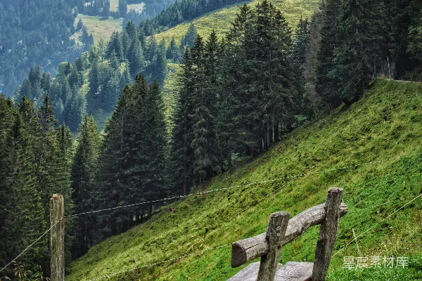 高清摄影 白天，棕色木栅栏位于绿草地上，周围是绿树和山脉。