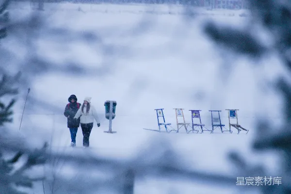 高清摄影 两个人从雪地里的雪橇旁走过。