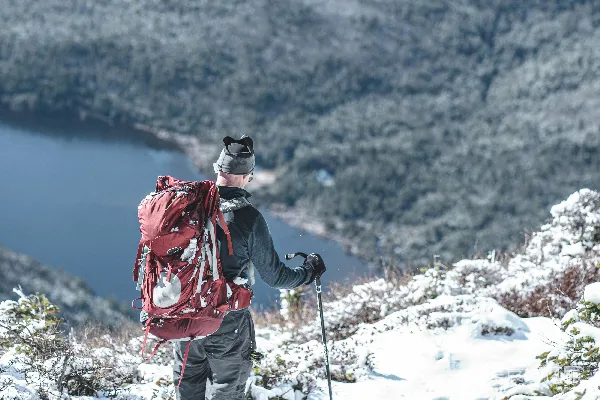 高清摄影 穿红色夹克和白色裤子的人站在白天被雪覆盖的山上。