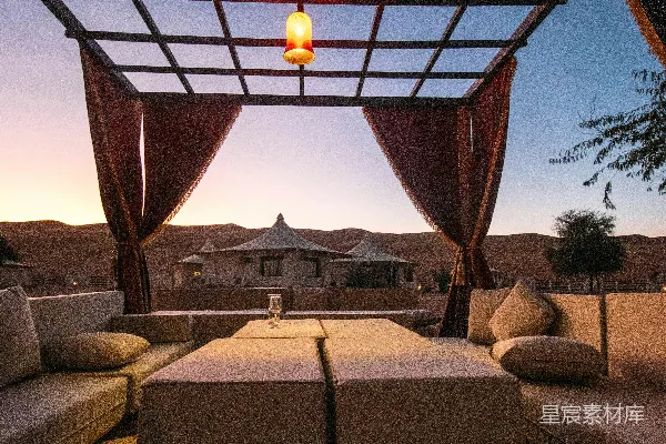 高清摄影 奢华的户外休息区，配有遮阳篷和沙漠日落。