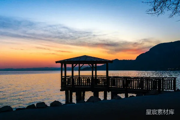 高清摄影 一个凉亭坐落在湖畔，夕阳西下时分。