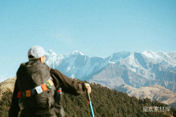 高清摄影 背着徒步杖的徒步者望着雪山。