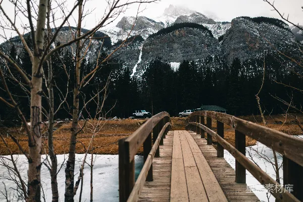 高清摄影 一座木桥通往雪覆盖的山景。