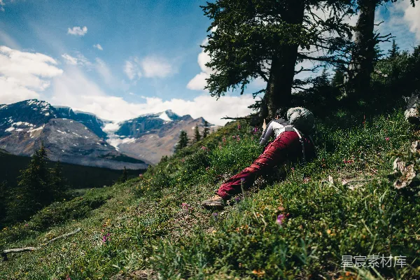 高清摄影 一个人在草地上休息，远处可以看到山脉的景色。