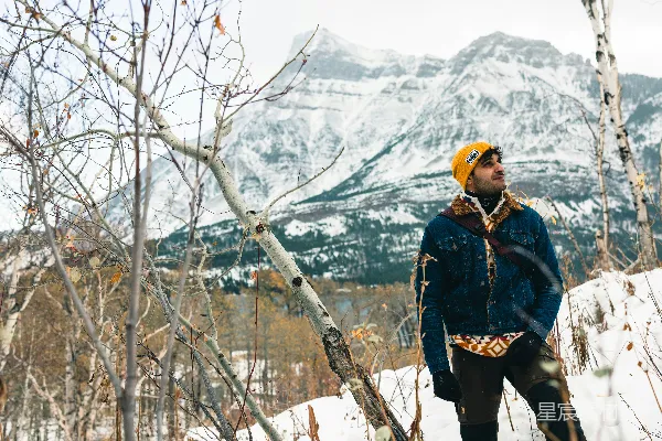 高清摄影 一个男人站在雪地里，面前有一座山。