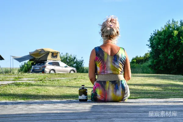 高清摄影 坐着的女人看着一辆带有露营顶篷的车。