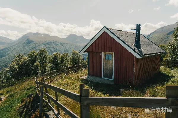 高清摄影 山上有一座红色的小屋，周围有山脉和栅栏。