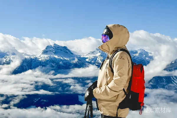 高清摄影 站在白雪覆盖的山顶上的滑雪者，俯瞰着云层。