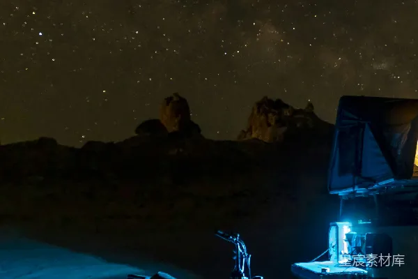 高清摄影 在星空下的沙漠夜晚，设置电动车和露营装备。