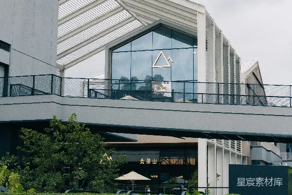 高清摄影 简洁现代的建筑，屋顶呈独特的三角形，周围环绕着绿植。