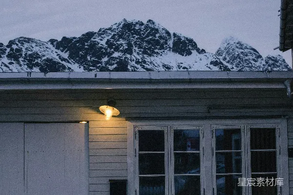 高清摄影 黄昏时分，一座小屋后方的雪山