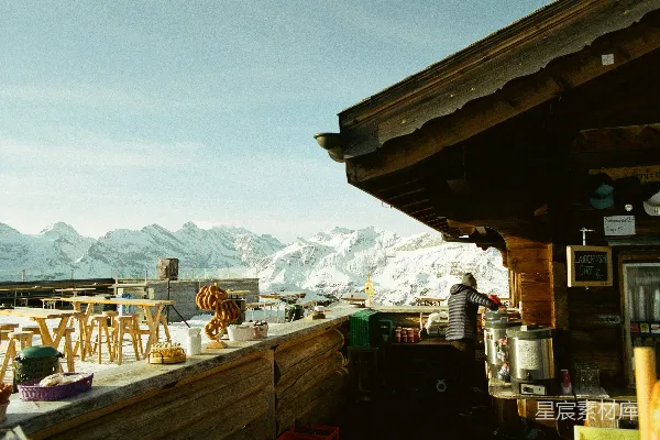 高清摄影 一个木制滑雪小屋，配有户外座位和雪山。
