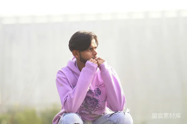 高清摄影 一个男人坐在滑板上，坐在土路上。