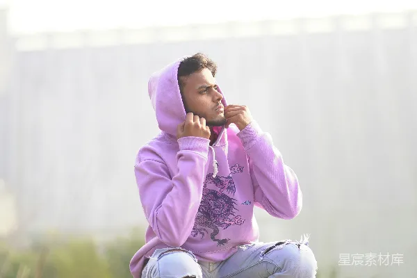 高清摄影 一个穿着紫色连帽衫的男人坐在滑板上