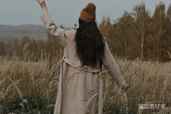 高清摄影 一个女人站在一片高高的草地上。