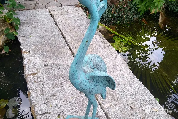 高清摄影 一座鸟雕像矗立在池塘附近的岩石上
