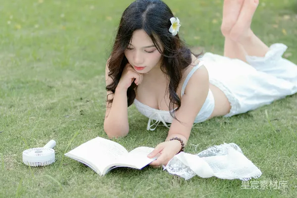 高清摄影 一位女子躺在草地上看书。
