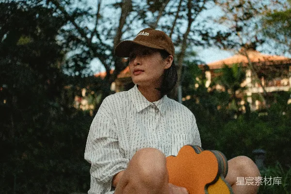 高清摄影 戴着棒球帽和条纹衬衫的女人坐在户外。