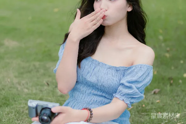 高清摄影 一个女人坐在草地上，拿着相机。
