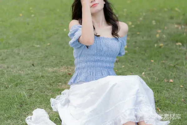 高清摄影 一个穿着蓝色连衣裙的女人坐在草地上