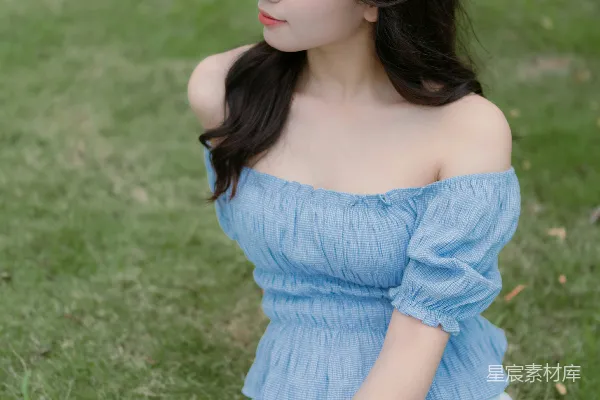 高清摄影 一个女人坐在草地上拿着相机。