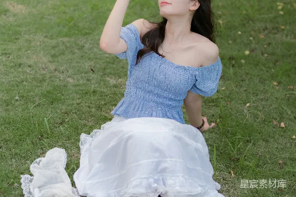 高清摄影 一位穿蓝色连衣裙的女士坐在草地上。