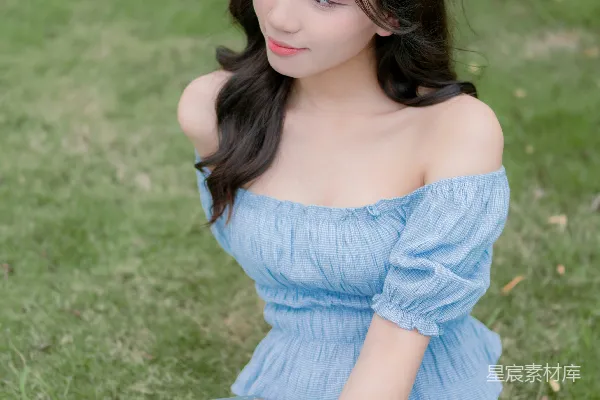 高清摄影 一个穿着蓝色连衣裙的女人坐在草地上。