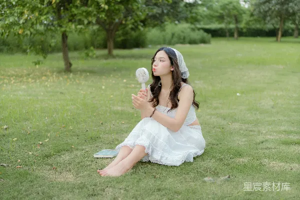 高清摄影 穿着白色连衣裙的女人坐在草地上。