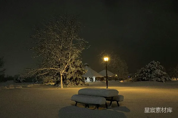 高清摄影 一张公园长椅在夜晚被积雪覆盖。