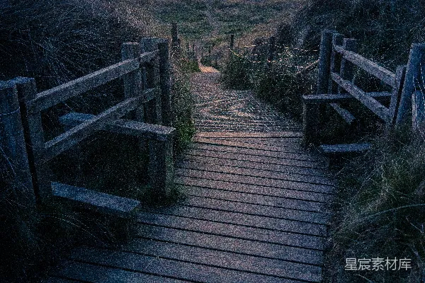 高清摄影 一条通往海滩的木制小径在日落时分。