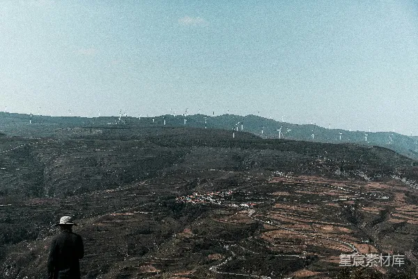高清摄影 一个男人站在一座山丘的顶端，旁边是郁郁葱葱的绿色山坡。