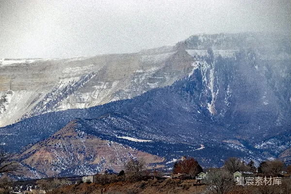 高清摄影 一座被雪覆盖的山，山前有房屋。