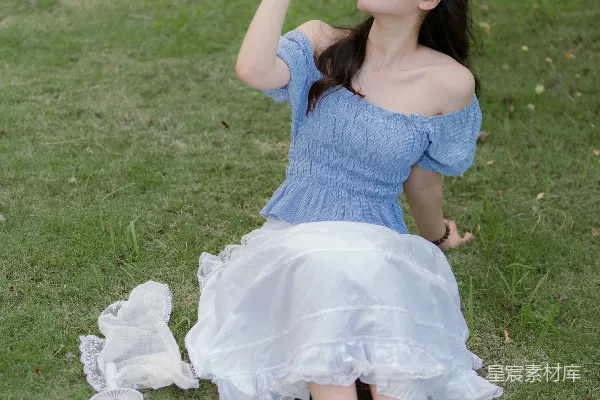 高清摄影 一位穿着蓝色连衣裙的女士坐在草地上。