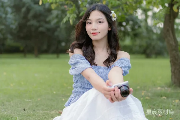高清摄影 一位女士坐在草地上，手里拿着一瓶酒。
