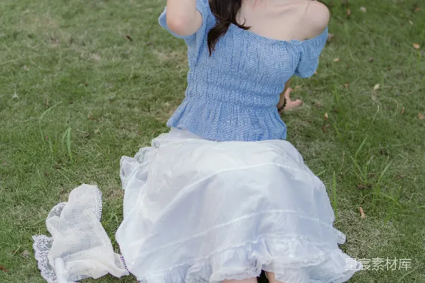 高清摄影 一个女人坐在草地上，手里拿着相机。