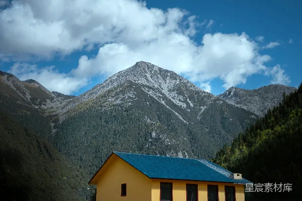 高清摄影 一座黄色的建筑，屋顶是蓝色的，山峦在背景中。