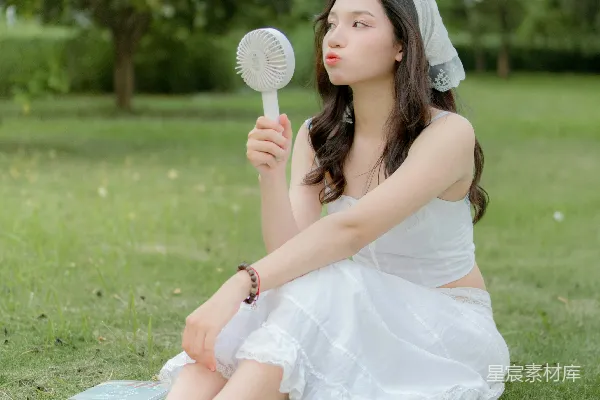 高清摄影 一位穿着白色连衣裙的女子坐在草地上。