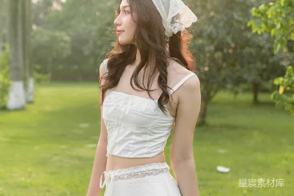 高清摄影 一位穿着白色连衣裙的女士站在草地上。