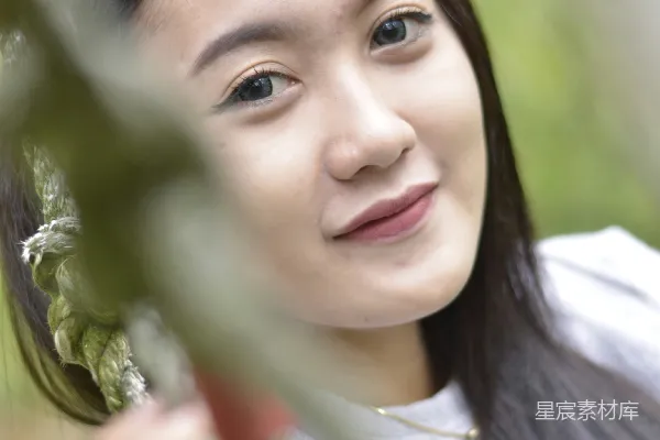高清摄影 一个女人一边抱着植物，一边微笑着。