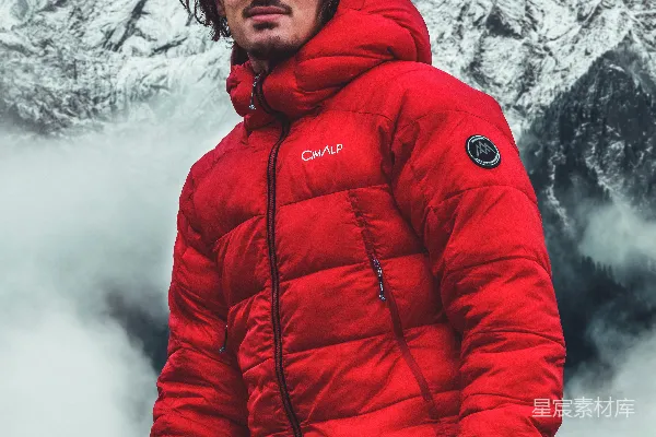 高清摄影 一位穿着红色外套的男子站在山前。