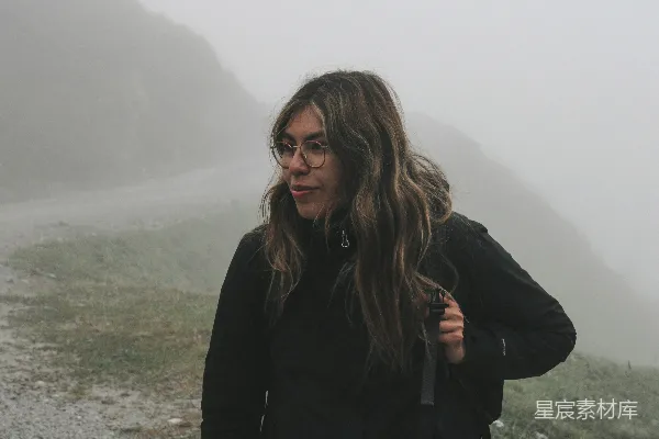 高清摄影 戴眼镜的女人站在雾蒙蒙的道路上。