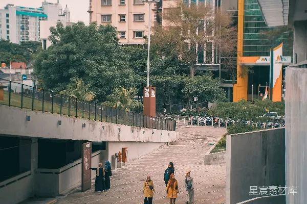 高清摄影 一群人在高楼旁边沿着街道行走。