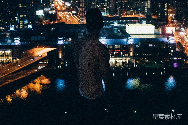 高清摄影 一个男人站在夜晚的城市天际线前。
